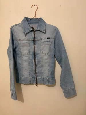 Ljusblå jeansjacka med dragkedja - Supersöt jeansjacka, lätt figursydd, dragkedja upp och nedtill kan blixtras på olika sätt, perfekt till vår o sommar 💕💕