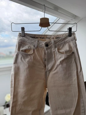 Beige wide jeans med hög midja - Säljer ett par beige jeans med regular wide fit och hög midja. Byxorna har raka ben. Midjemått 26, längd 32. Perfekta för en avslappnad och trendig stil. Dessa är aldrig använda. 