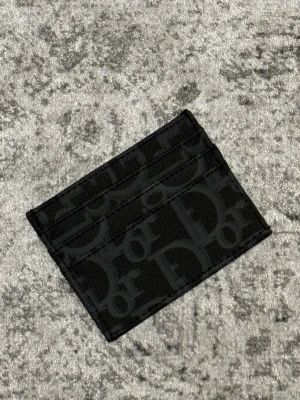 Svart korthållare - Snygg svart korthållare med ikoniskt monogrammönster. Tillverkad i tålig canvas med flera kortfack på båda sidor. Perfekt för dig som vill ha en stilren och lyxig accessoar i fickan.