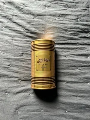Jean Paul Gaultier Le Male Elixir - Säljer en lyxig parfym, Jean Paul Gaultier Le Male Elixir. Flaskan har en unik guld- och svart design i form av en manlig torso med röd bas, och kommer i en guldfärgad metallburk. Perfekt för dig som gillar exklusiva dofter och snygg design.  Nästan heöt full inte använd mycket 