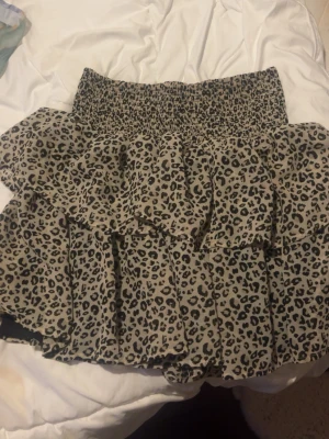 Leopardmönstrad volangkjol - Säljer en kort volangkjol med leopardmönster. Kjolen har bred resår i midjan och flera lager volanger som ger en cool och trendig look. Perfekt för dig som vill sticka ut lite extra.