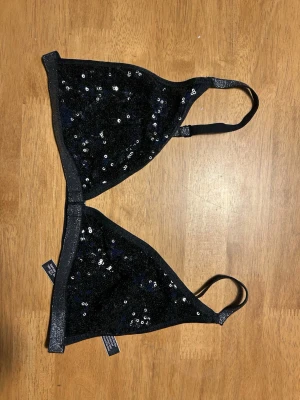 Bralette med paljetter  - Bralette med paljetter från Victoria’s Secret. Skönt material på insidan så man sticks inte av paljetterna. Öppning fram. Endast använd ett fåtal gånger. Är i storlek L men har passat mig som har 75B.
