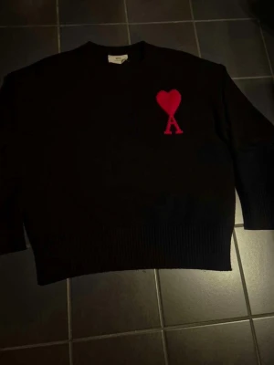 Svart stickad tröja Ami Paris - Säljer en authetiskt stickad tröja från Ami Paris | I färgen svart med röd logga och storlek S | Inga defekter | Hör av er för mer information/bilder!