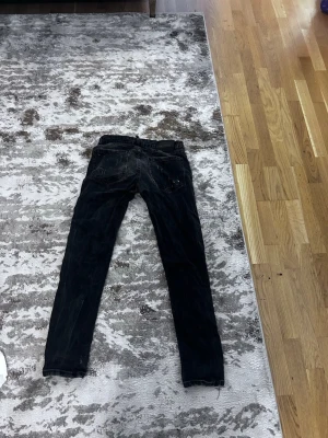 Disquard jeans - Säljer ett par svarta skinny jeans med coola slitningar och vita färgstänk på framsidan. Jeansen har klassiska fem fickor och dragkedja. Perfekt för dig som gillar en edgy och trendig look.