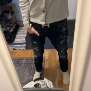 Replay mörkblå slitna jeans - Mörkblå jeans från Replay, med snygga slitningar och distressed detaljer framtill och baktill. Klassisk femficksdesign, smal passform och tydliga kontrastsömmar. Perfekta för dig som vill gå med stil 