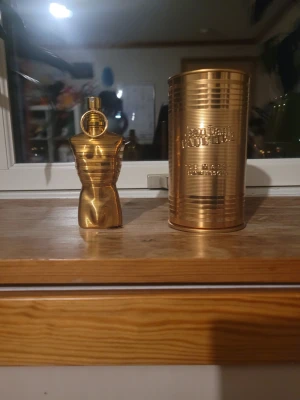 Jean Paul Gaultier Le Male Elixir Absolu - Lyxig herrparfym från Jean Paul Gaultier i en ikonisk guldfärgad flaska formad som en manlig torso. Kommer med en matchande guldfärgad metallburk med präglad logga. Flaskan har en elegant och modern design som verkligen sticker ut. Knappt använd.