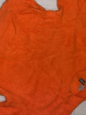 Orange stickad tröja från H&M Divided - Snygg orange stickad tröja från H&M Divided. Tröjan har rund halsringning och ribbstickade muddar vid hals, ärmslut och nederkant. Perfekt för dig som vill ha en färgstark och mysig look.