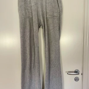 Grå mjukisbyxor från Juicy Couture  - Grå mjukisbyxor med raka ben och fickor både fram och bak. Byxorna har normal passform och är tillverkade i mjukt bomullsmaterial, perfekta för en avslappnad stil. Små slitningar här å där (vid knäna) använt skick. 