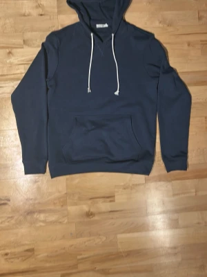 Pier one hoodie  - Snygg mörkblå hoodie från pier one med klassisk känguruficka och vita dragsnören i huvan. Hoodien har ribbade muddar vid ärmslut och nederkant. Perfekt för en avslappnad och stilren look. Materialet känns mjukt och bekvämt mot huden.