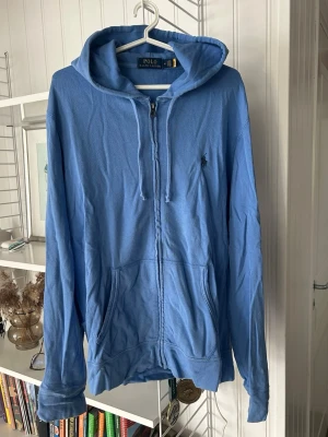 Blå ziphoodie från Polo Ralph Lauren - Blå zip-hoodie från Polo Ralph Lauren med klassisk huva och dragkedja. Använd 1 gång och sedan har den legat i garderoben så kände att det var dax att den fick bättre användningsområde. Bara att höra av sig vid frågor etc. Nypris var mellan 1999-2400 säljer den för 1299kr