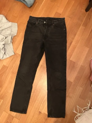 Svarta raka jeans från Carlings - Säljer ett par svarta jeans i rak modell. Klassisk femficksdesign med knapp och dragkedja framtill. Jeansen har en enkel och stilren look som passar till det mesta. Materialet är denim med en mjuk känsla. Passformen är vailent