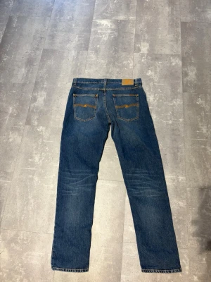 Nudie Jeans - Säljer ett par klassiska blå jeans från Nudie Jeans med raka ben och snygga kontrastsömmar på bakfickorna. Jeansen är aldrig använda och är köpta för 1600! Modellen är solid ollie