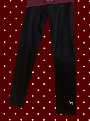 Svarta leggings från Victoria's Secret - Säljer ett par svarta leggings från Victoria's Secret Pink med den ikoniska lilla hundloggan nere vid benet. De har en tight passform och är tillverkade i ett stretchigt material som sitter skönt hela dagen.