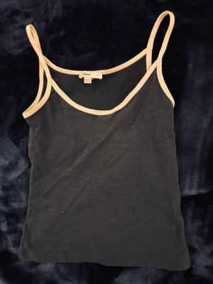 Subdued linne - Snygg mörkblått linnetopp från Subdued med tunna axelband och kontrasterande ljusrosa kant runt halsringning och axelband. Perfekt att styla lager på lager eller till jeans. Mjuk och stretchig känsla. Använd 1 gång.