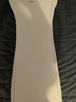 Lång beige klänning - En stilren beige klänning med korta ärmar och rund halsringning. Klänningen har en rak passform och är tillverkad i ett mjukt, stretchigt material som känns bekvämt mot huden. Perfekt för dig som gillar en enkel och clean look. Väldigt skön att ha i vardagen, samtidigt ett bra plagg att träffa vänner med. Står S på klänningen men passar xs och xxs. Säger det som själv haft den när jag varit i de storlekarna.