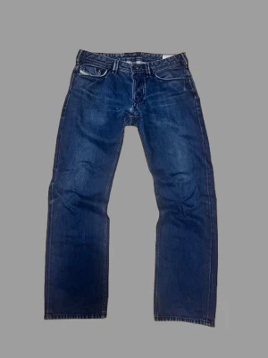 Diesel jeans  - Säljer ett par klassiska blå jeans med rak passform och snygga broderade detaljer på bakfickorna. Jeansen har normal midja och fem fickor. Perfekta till vardagslooken och tillverkade i slitstark denim.