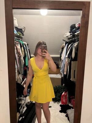 Gul omlottklänning med knyt - Snygg gul kortklänning med omlott-design och knyt i midjan. Klänningen har v-ringad hals och är ärmlös, vilket ger en fräsch och ungdomlig look. Perfekt för sommarens alla tillfällen! Använt 1 gång. Köpt för 400, säljer för 100 (pris går att diskutera)