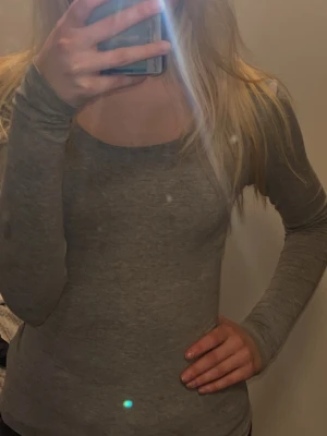 Grå långärmad topp i bomull - En enkel och stilren grå långärmad topp med rund halsringning. Tillverkad i mjuk bomull som sitter skönt mot kroppen. Perfekt att matcha med jeans eller kjol för en clean look.