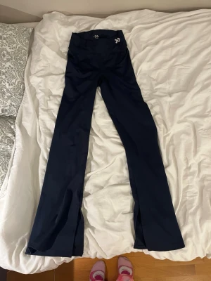 Mörkblå bootcut leggings Aim'n - Säljer ett par mörkblå leggings från Lager 157 med bootcut-modell och hög midja. Tillverkade i stretchigt material som sitter skönt och följer kroppen. Perfekta för dig som gillar en stilren look med lite vidare ben. Dem har en snitt k slutet av benen och har träningsmatrial