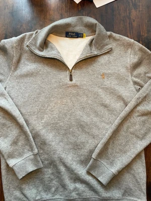 Ralph Lauren quarter zip - Supersnygg grå quarter zip från Polo Ralph Lauren i en mjuk och lyxig kvalitet. Klassisk och stilren design som funkar perfekt både till vardags och jobb. Storlek L - väldigt fin passform 🤎  Pris: 599 kr Nypris: ca 1 499 kr  Skick: Mycket bra! Skickas inom 24 timmar 📦🚚Välj helst Instabox vid frakt!