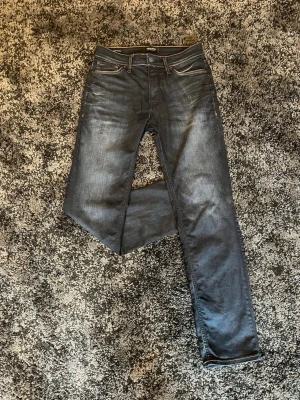 W29/L32 Mörkblå regular fit jeans från Jack&Jones  - Snygga mörkblå regular fit jeans från Jack&Jones med klassisk femficksdesign och kontrastsömmar. Jeansen har en rak passform och är tillverkade i denim med lätt tvättad look. Perfekta för dig som gillar stilrena och moderna jeans.