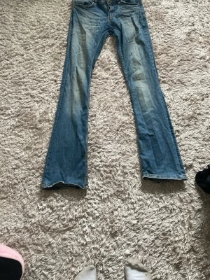 Blå bootcut jeans från g perfect jeans - Snygga blå bootcut jeans från g perfect jeans i storlek 36. Jeansen har klassisk femficksdesign, ljus tvätt med slitningar på låren och är tillverkade i denim. Perfekta för dig som gillar en retroinspirerad look med utsvängda ben.