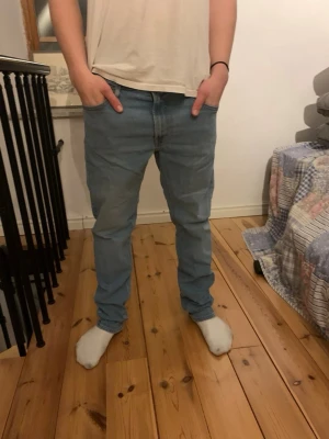 Ljusblå Lee jeans med rak passform - Säljer ett par ljusblå jeans från Lee med klassisk rak passform och fem fickor. Jeansen har gylf med knapp och dragkedja samt Lee-logga på linningen. Perfekta för en avslappnad och stilren look.