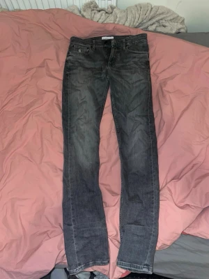 Calvin Klein jeans W29 L34 - Snygga svarta jeans från Calvin Klein med rak passform och klassisk femficksdesign. Jeansen har diskreta slitningar och logga på myntfickan. Perfekta för en stilren och avslappnad look. 