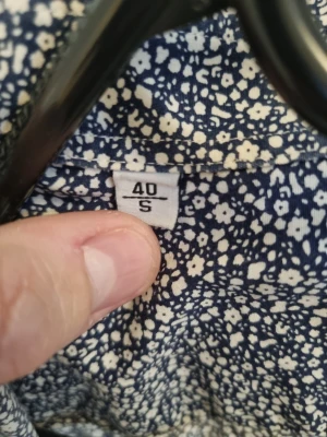 Blommig skjorta Selected Homme S - Mörkblå skjorta från Selected Homme med vitt blommigt mönster. Slim fit-modell som ger en snygg och modern siluett. Perfekt för dig som gillar stilrena detaljer och vill sticka ut lite extra.