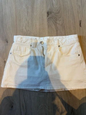 Vit jeanskjol från strandivarius 36 - Säljer en vit kort jeanskjol från strandivarius med klassisk femficksdesign, bälteshällor och knapp- samt dragkedjestängning framtill. Kjolen har raka linjer och är perfekt för en fräsch och enkel stil. Storlek 36 men liten i storlek💕