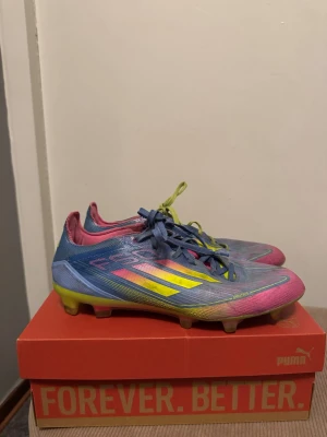 Adidas F50 färgglada fotbollsskor - Säljer ett par Adidas F50 fotbollsskor i en riktigt färgstark design med blå, rosa och gula detaljer. Skorna har användts men är fortfarande lika bra som när jag köpte de bara lite slitna, en sko har ett annat snöre eftersom den vanliga gick sönder.
