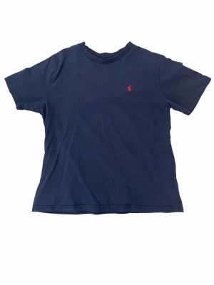 Marinblå t-shirt från Ralph Lauren - Klassisk marinblå t-shirt från Ralph Lauren med den ikoniska röda broderade loggan på bröstet. Stil ren för ett bra pris. Priset kan diskuteras vid snabb affär 
