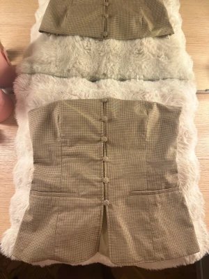 Zara topp - Säljer en superfin topp från Zara i storlek XS. Beige/brunrutig modell med figursydd passform, dekorativa knappar framtill och peplumdetalj som framhäver midjan på ett fint sätt. Endast använd en gång🤍  Hör av dig vid frågor! 
