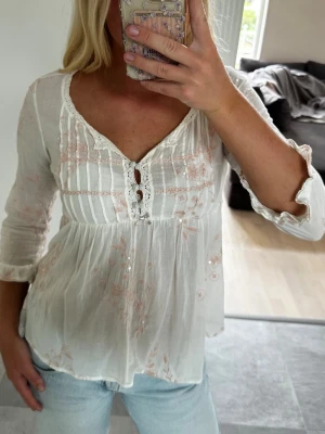 Odd Molly Blus - Säljer den mest perfekta blusen då den tyvärr blivit för liten (😭, Om du säljer en i strl 2 skriv snälla). Den är vit med rosa broderier, paljetter, 3 knappar och 1 rosett framtill. Trekvarts armar med volanger och en så fin passform. Sparsamt använd vid ett fåtal gånger och inga defekter.  Strl 0 vilket motsvarar XS. 
