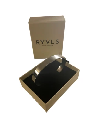 Silvrigt armband från RYVLS - Stilrent och minimalistiskt armband i silverfärgad metall från RYVLS Stockholm. Armbandet har en öppen design och levereras i en snygg ask med logga. Perfekt accessoar för dig som gillar enkel och modern stil.
