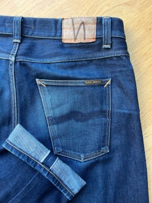 Nudie selvege faded jeans L36 - Är i modellen Gritty Jackson vilket är en straight modell. Dem är andvända i ~1 år och tvättade tre gånger just nu är dem nytvättade. Dem är lagade i skrevet hos Nudie reapair shop. Jag är 192 cm och 85 kg. Passat alla runt 190 skulle jag säga. Den lägger sig fint på skor. Alla mått finns på nudies hemsida fast dem har krympt någon CM i midjan och på längden som selvege gör. W34 L36