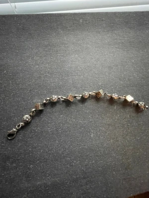 Chrome hearts armband - Unikt armband i silverfärg med växelvis mönstrade runda stenar och små fyrkanter. Armbandet har en enkel karbinhake och coola detaljer som ger en personlig touch. Perfekt för dig som gillar accessoarer med lite edge.