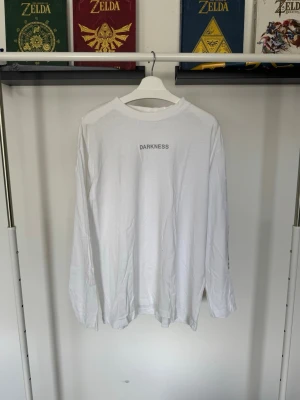 Vit långärmad tröja Eternal Youth - Vit långärmad topp från Eternal Youth med tryck på bröstet, ryggen och ena ärmen. Tröjan har en avslappnad och oversized passform och är tillverkad i mjuk bomull. 