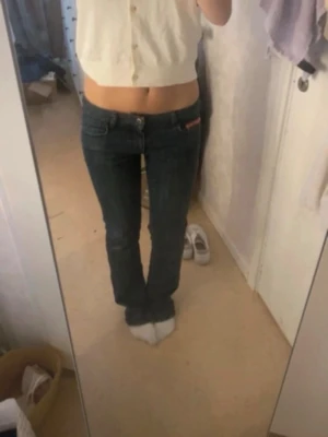 Mörkblåa lågmidjade jeans med rosa detaljer  - Säljer ett par lågmidjade blåa jeans i storlek M (men passar bäst S/XS)  Säljer då de inte riktigt passade och för att säljaren jag köpte av inte berättade att de var klippta längst ner (se bild)  Midja = 38 cm ungefär  Innerbenslängd = 79 cm (med den uppklippta delen, utan = ungefär 70cm)  Den uppklippta delen tror jag att man kan sy ihop om man skulle vilja det🥰❤️