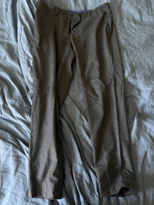 Grå kostymbyxor från Massimo Dutti - Snygga grå kostymbyxor från Massimo Dutti med klassisk rak passform. Tillverkade i Portugal och har diskreta fickor i sidorna. Perfekta för en stilren och modern look. Materialet känns mjukt och exklusivt.