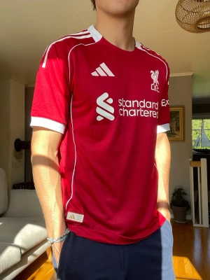Liverpool FC Hemmatröja 2025/26 – Adidas – Mycket fint skick - Säljer en Liverpool FC hemmatröja från säsongen 2024/25 från Adidas. Tröjan är i mycket fint skick och har bara använts ett fåtal gånger. Perfekt för dig som supporter eller samlare.  • Liverpool FC hemmatröja 2024/25 • Adidas original • Standard Chartered sponsortryck • Fint skick utan hål eller skador • Bekvämt och ventilerande material • Snygg passform  Storlek: M (L men passar som M) Pris: 449 kr