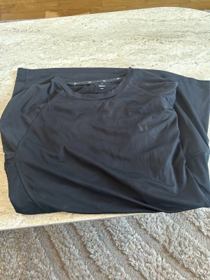 Svart tränings-tshirt från MP - Säljer en svart tränings-tshirt från MP med rund hals och diskret logga på bröstet. Tillverkad i ett lätt och stretchigt funktionsmaterial som passar perfekt för gymmet eller löprundan.