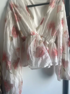 Gina tricot blus - Fin blommig blus i ett ”glansingt” material med en v-ringning i storlek 34. Använd ett fåtal gånger.