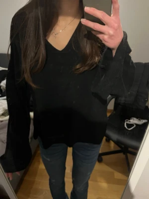 Svart v-ringad stickad tröja - Säljer en svart stickad tröja med v-ringning och långa ärmar. Tröjan har en avslappnad passform.