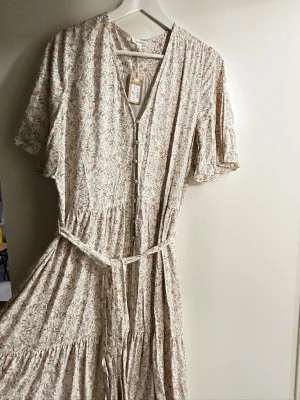 Newbie klänning - Helt oanvänd Newbie klänning i storlek M. Super fin modell med vida korta armar samt knytband i midjan. Nypris 1199kr.