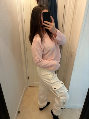 Vita cargobyxor med dragsko - Säljer ett par vita cargobyxor med dragsko i midjan och flera fickor på sidorna. Byxorna har en avslappnad passform och är perfekta för en trendig streetstyle-look. Materialet ser ut att vara bomull eller bomullsblandning. Snygga och bekväma för dig som gillar casual mode.