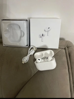 AirPods Pro gen 2 - Säljer ett par vita trådlösa in-ear hörlurar från Apple, modell AirPods Pro. Hörlurarna har en stilren och kompakt design med silikonproppar och laddningsetui. Medföljer laddningskabel och originalförpackning. Perfekta för musik, samtal och träning.