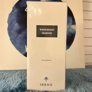 White Regent Diamond parfym från IBRAQ  - White Regent Diamond Eau de Parfum från IBRAQ i en stilren, rektangulär vit förpackning med svart etikett. Doften kommer i en elegant kartong som ger en lyxig känsla och passar perfekt för dig som gillar exklusiva parfymer.