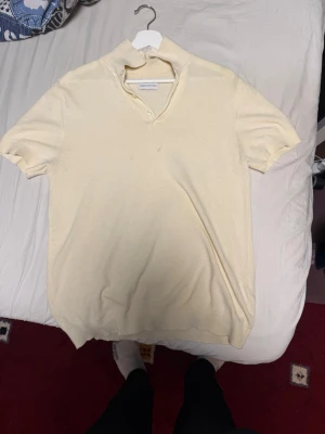 Beige kortärmad polotopp från Our Legacy - Säljer en beige polotopp från Our Legacy med korta ärmar och mjukt material. Toppen har en unik krage med två knappar och en avslappnad passform. Perfekt för dig som gillar stilrena och minimalistiska plagg.