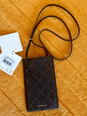 By Malene Birger Ivy - Dark Chocolate - Helt ny med tags kvar enligt bilder.  Mått: H 17 x B 10 cm   Färg: Dark Chocolate  Axelrem och kanter i läder  Längd axelrem: 112cm  Se gärna mina övriga annonser för bundlerabatter och samfrakt!